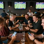 Excited fans engaging in SHBET sports betting at a vibrant sports bar.