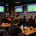 Betting on nhandinhkeo with friends in a lively sports bar, screens showing live odds