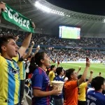 Cheering fans at a soccer match enjoying nowgoal live score updates in an exciting stadium atmosphere.
